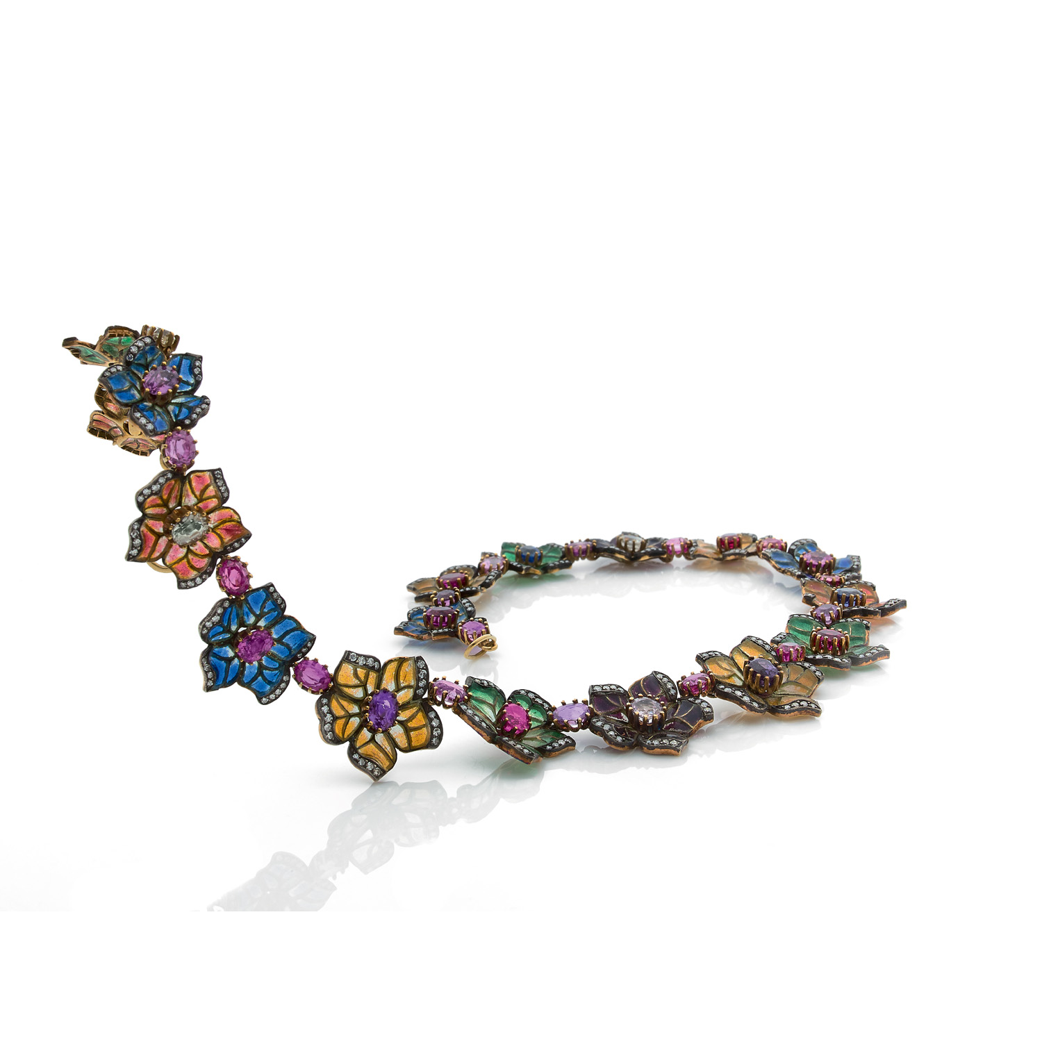 Collier draperie "Pens&eacute;es" en or jaune 18k (750&permil;) compos&eacute; de 17 fleurs orn&eacute;es d'&eacute;maux translucides plique &agrave; jour et soulign&eacute;es de diamants Les fleurs sont r&eacute;unies entre-elles et serties au centre de rubis et de saphirs multicolores de forme ovale Fermoir en "S" en or jaune Poin&ccedil;on d'occasion France (hibou) Diam&egrave;tre int&eacute;rieur : 10,5 cm Poids brut : 67,2 g
