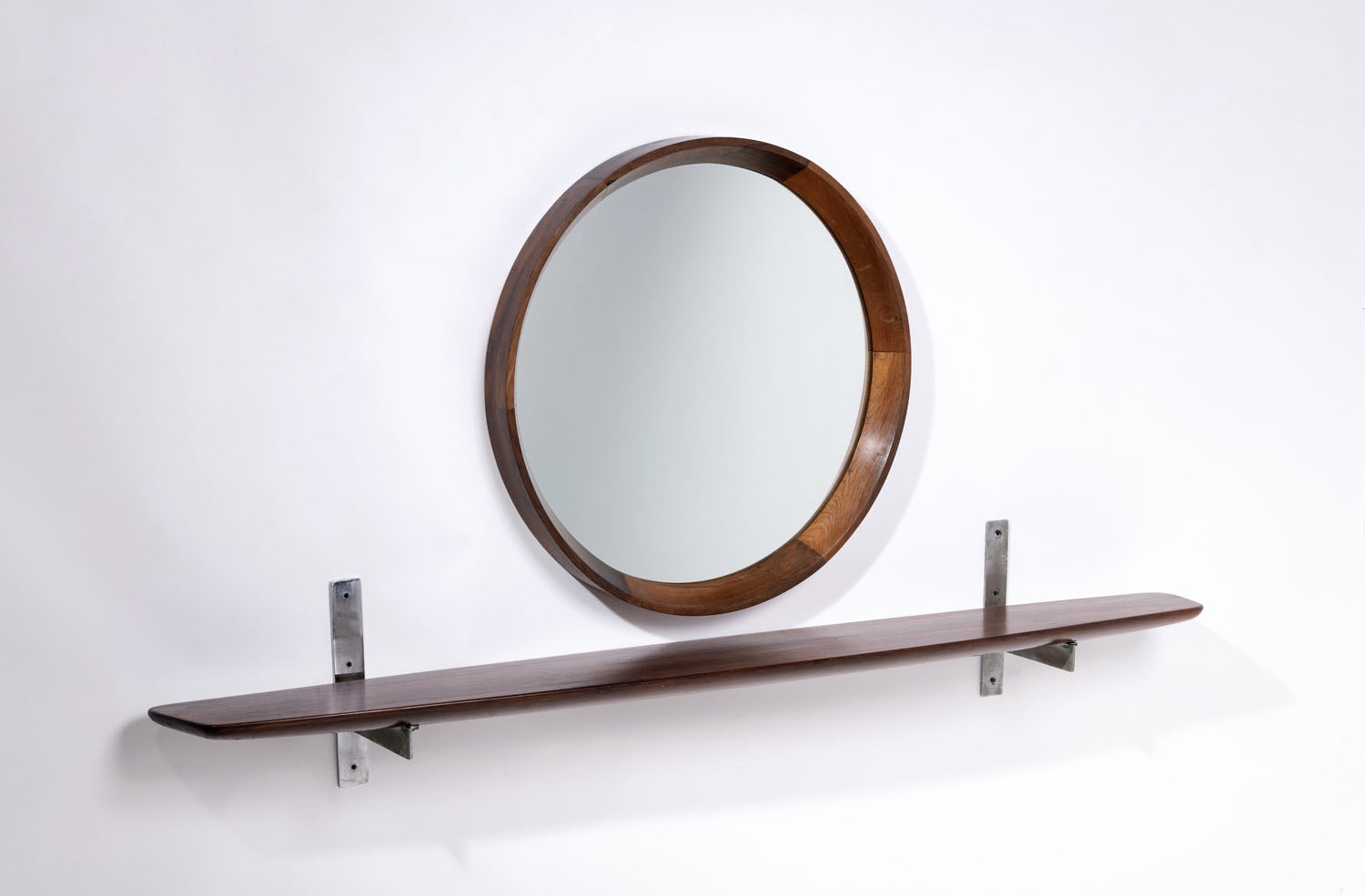 Sergio Rodrigues (1927-2014) Grasselli Estimation : 5000 / 7000 &euro; Sergio Rodrigues (1927-2014)  Grasselli  Miroir et console murale  M&eacute;tal, bois d'imbuia et miroir  Edition Oca  Date de cr&eacute;ation: ann&eacute;es 1960  Miroir : &Oslash; 80  &times;P 7,5cm  Console : H 33  &times;L 200  &times;P 24cm  Bibliographie : S. Cals, "Sergio Rodrigues",  catalogue raisonn&eacute;, Ed. Icatu, 2000, Rio de  Janeiro, p. 260