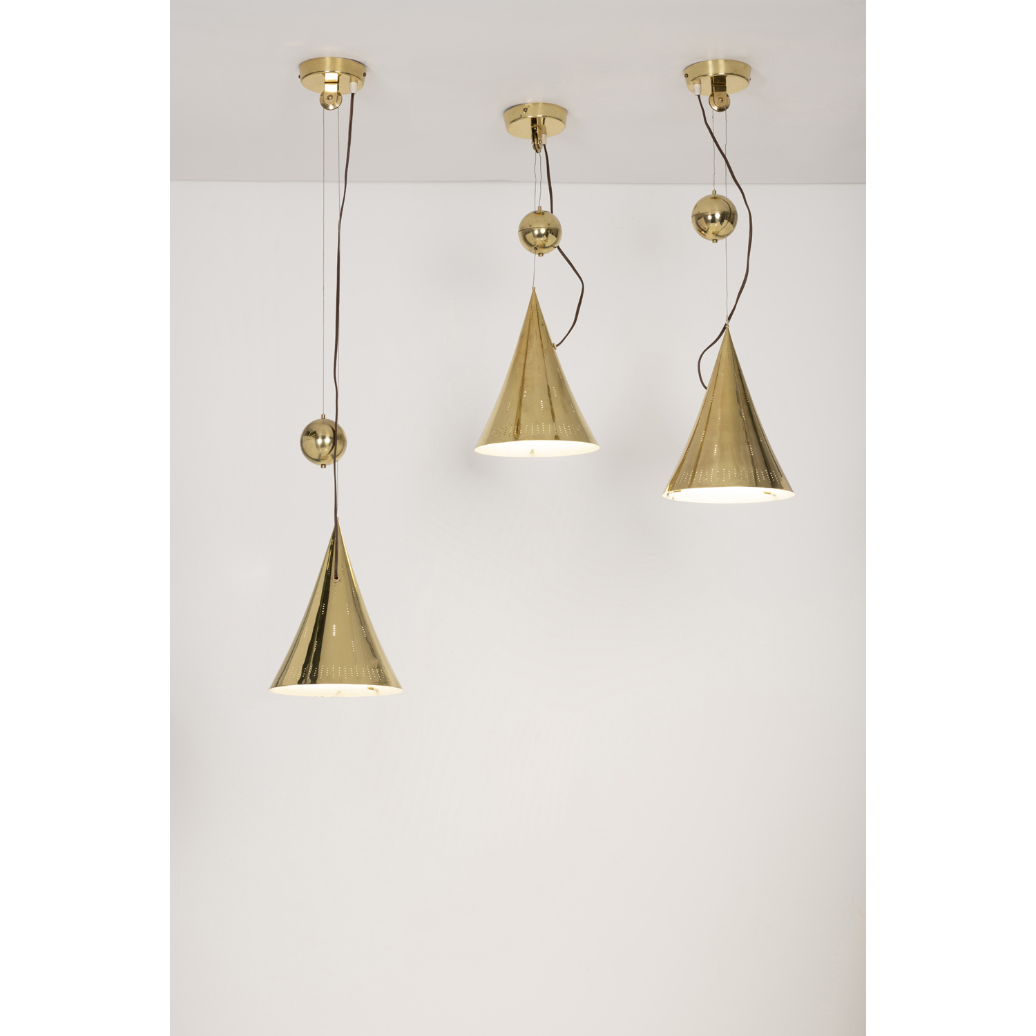 Paavo Tynell (1890-1973) Modèle n°10220 Suite de trois suspensions Laiton et verre Édition Taito Oy pour Finland House, New York Modèle créé à la fin des années 1940 H (variable) 117× Ø 25,5 cm  Model n°10220 Three ceiling lamps Brass and glass Edition Taito Oy for Finland House, New York Model created in the late 1940's H (adjustable) 46 × Ø 10 in.
