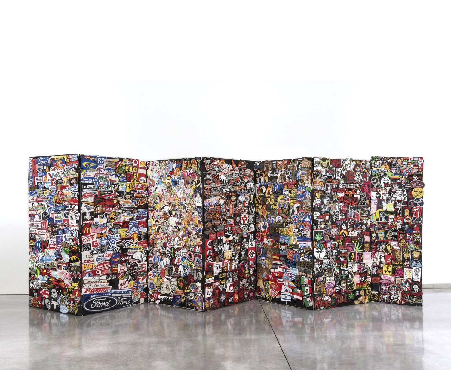 Claire Fontaine (collectif fondé en 2004) Multitude, 2008 Paravent composé de de 7 panneaux de patchs sur toile sur structure métallique 101 x 297 x 42 cm Provenance: - Galerie Neu, Berlin - Collection particulière, Bruxelles Expositions: - Berlin, Galerie Neu, "Change", 12 Juillet - 23 Août 2008