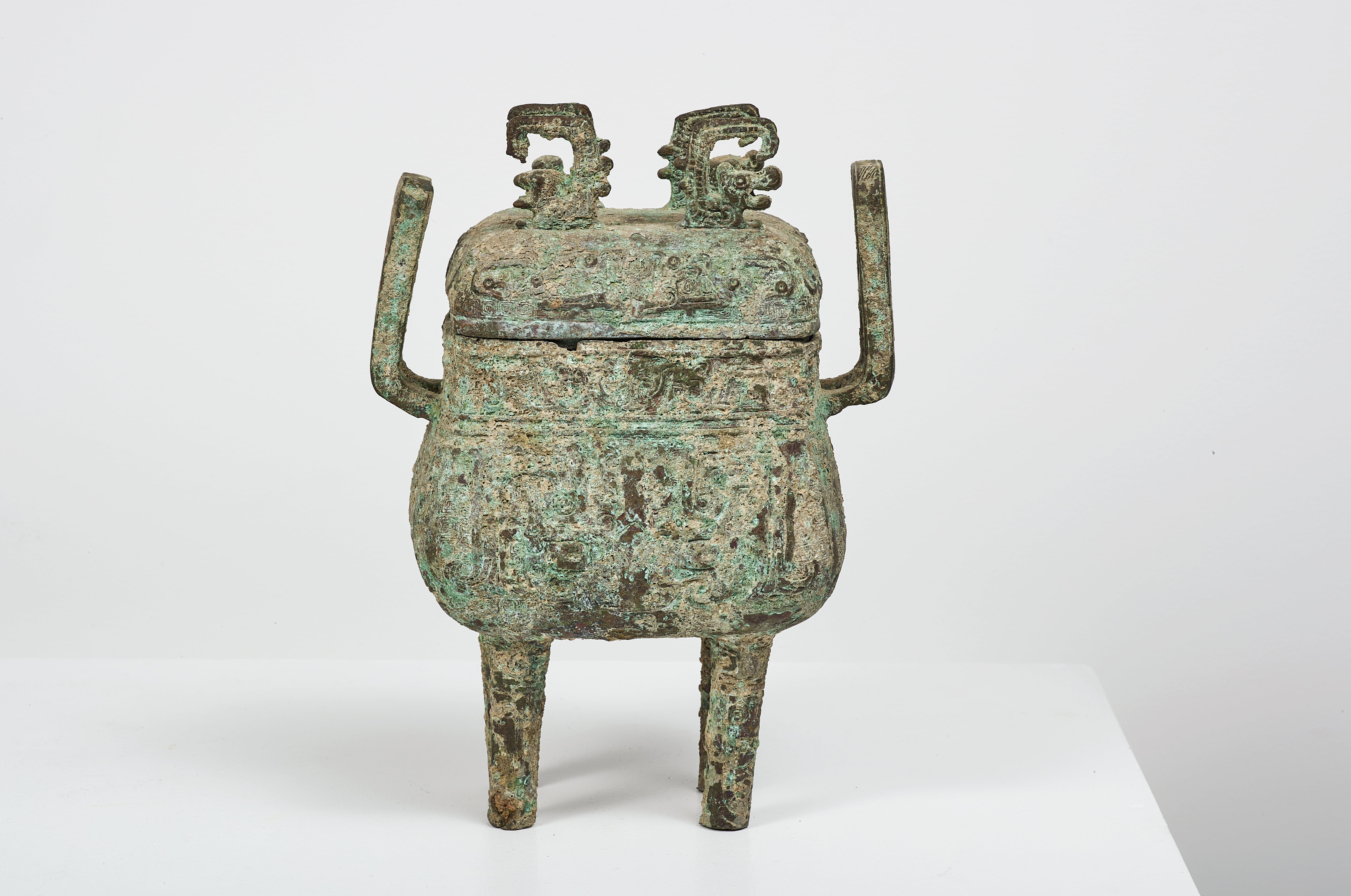 China, in the shang style Fang Ding covered quadripod in archaic bronze. The lid surmounted by four stylized dragons in high relief.