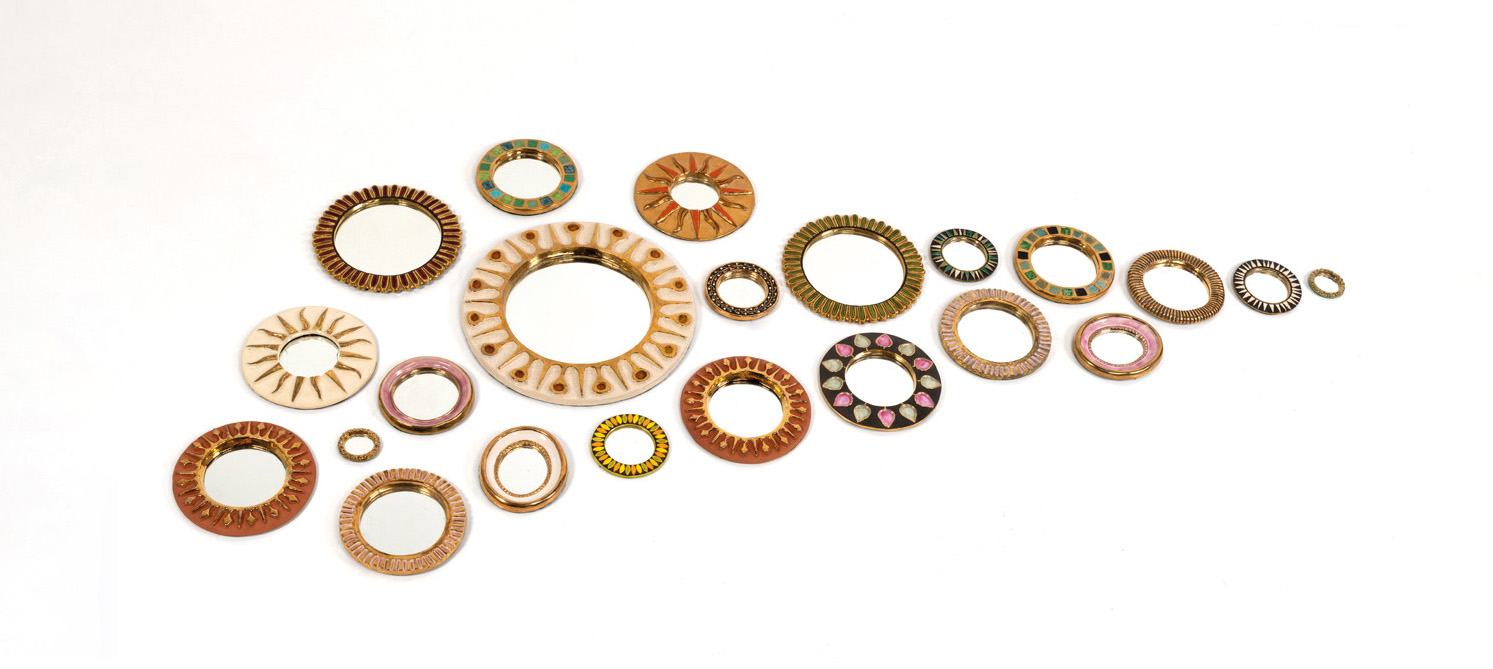 Mith&eacute; Espelt (1923-2020) Ensemble compos&eacute; d'un miroir mod&egrave;le 'Soleil' et de vingt-un miroirs circulaires C&eacute;ramique &eacute;maill&eacute;e rehauss&eacute;e d'or et p&acirc;te de verre Mod&egrave;les cr&eacute;&eacute;s entre 1950 et 1955 Le plus grand: &Oslash; 48 cm Le plus petit: &Oslash; 8 cm