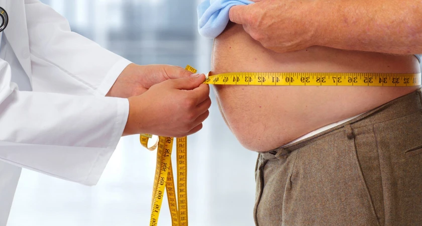 Un médecin mesure le tour de taille d'un patient avec un ruban à mesurer.