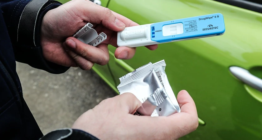 Test salivaire pour drogues à côté d'une voiture verte.