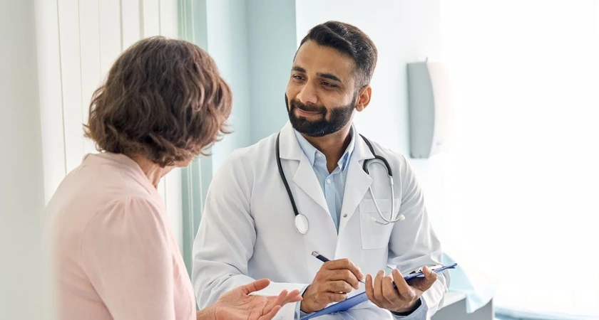 Médecin souriant discutant avec une patiente dans un cabinet médical.