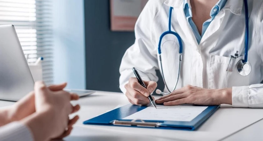 Médecin en blouse blanche prenant des notes lors d'une consultation.