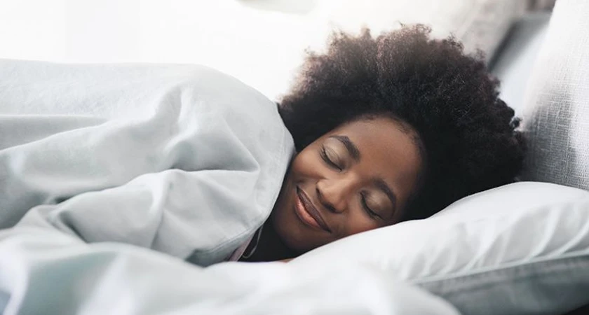 Personne souriant en dormant paisiblement sous une couverture blanche.