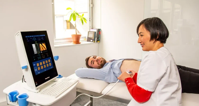 Examen médical avec échographie réalisé par un professionnel de santé sur un patient allongé.