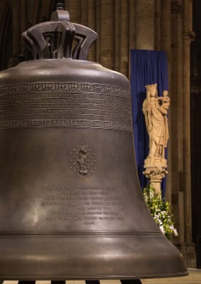 Gros plan sur le petit bourdon, dit "bourdon Marie" avec la statue de la Vierge à l'enfant en arrière plan