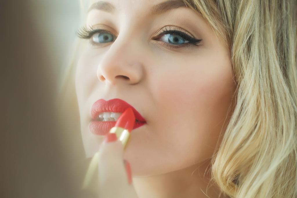 Une femme se maquille avec du rouge à lèvre
