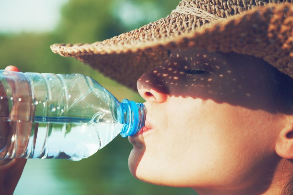 Eine Frau, die sich in der Sonne mit Wasser rehydriert