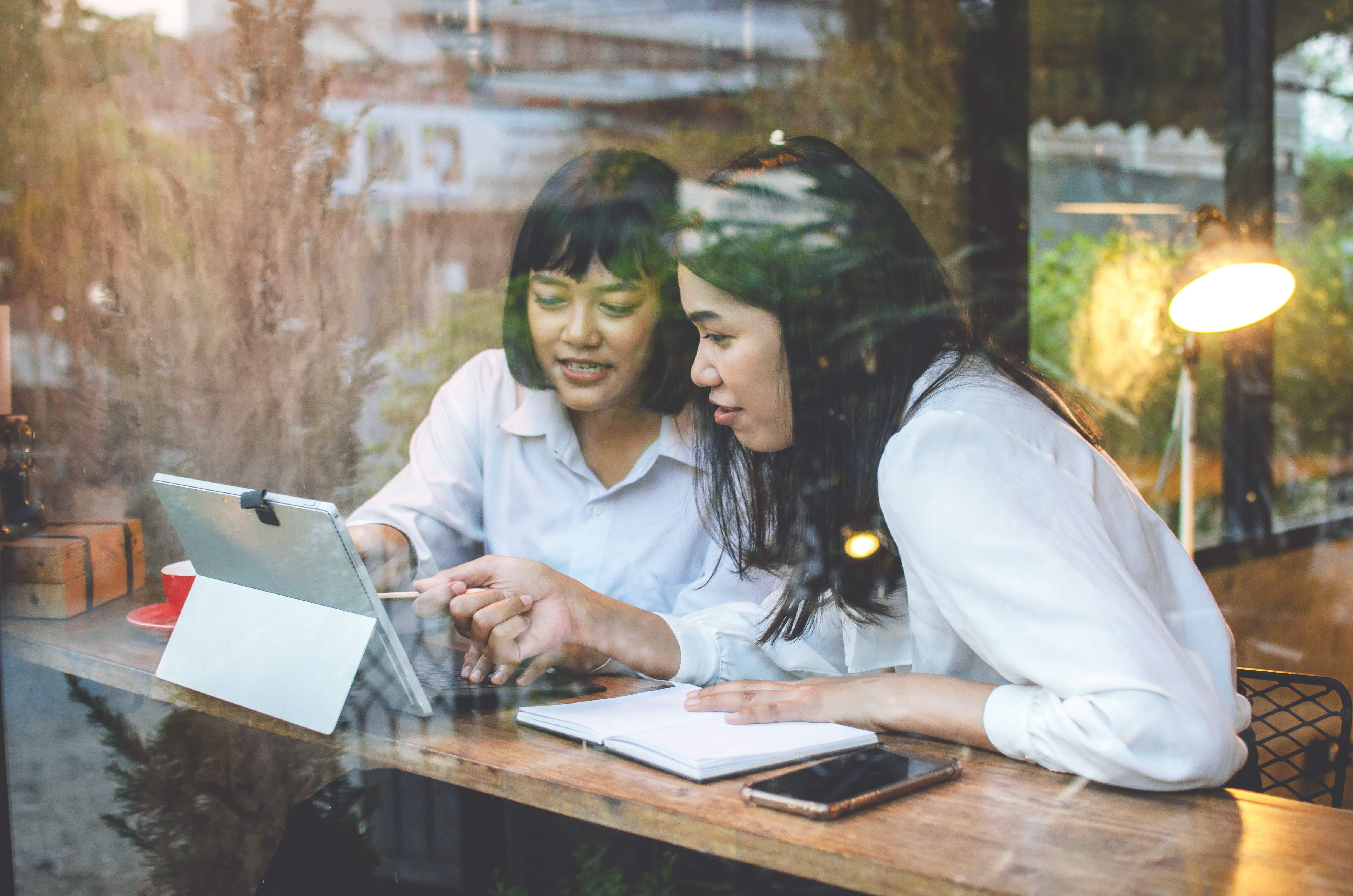 two woman at a work meeting reviewing a document on a tablet