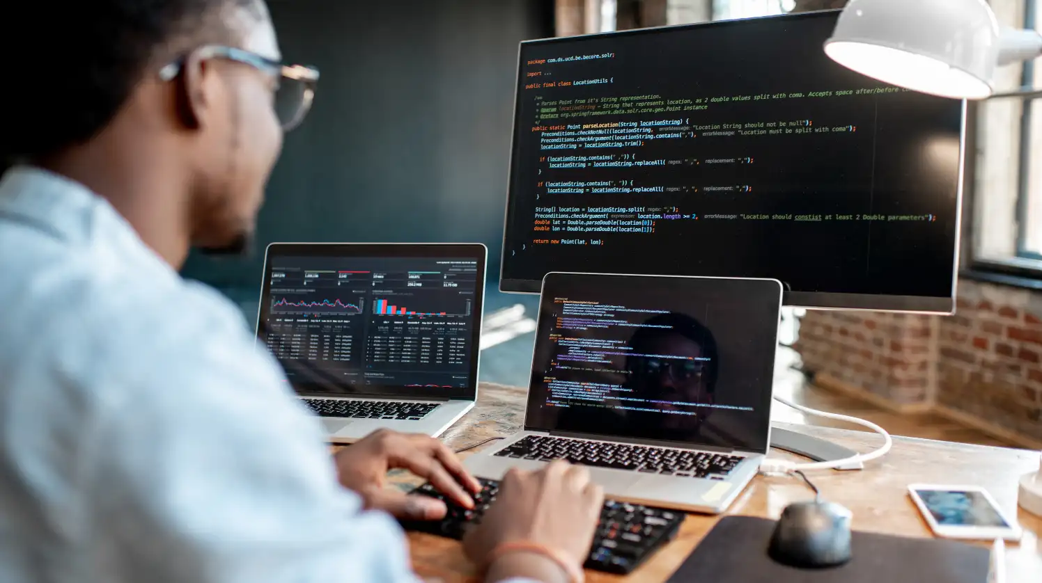 An engineer is working with an Oracle system with three monitors opened in front of him