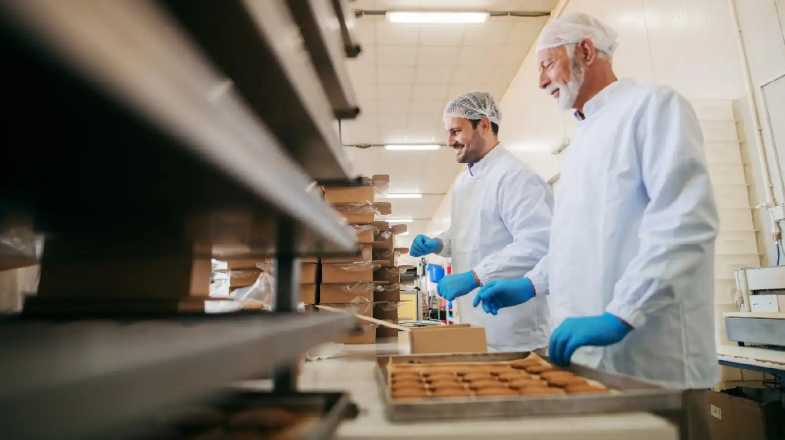 Workers packing cookies in boxes while standing in food factory.