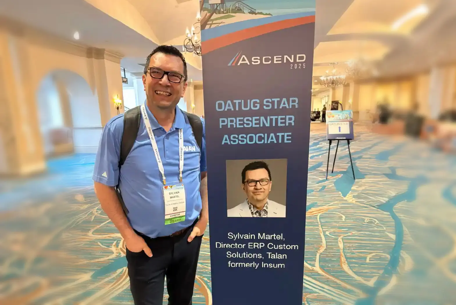 Sylvain at the Ascend2025 next to a poster of himself