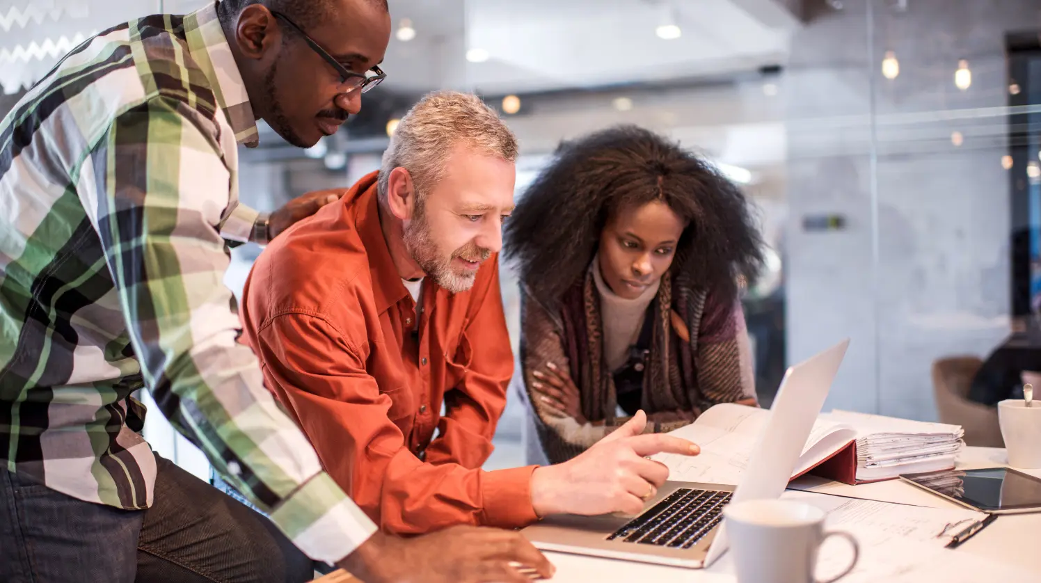 A team at the office looking at a computer and discussing a project