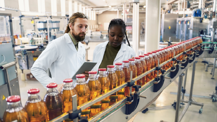 Femme et homme sur une ligne de production de bouteilles jaunes.  