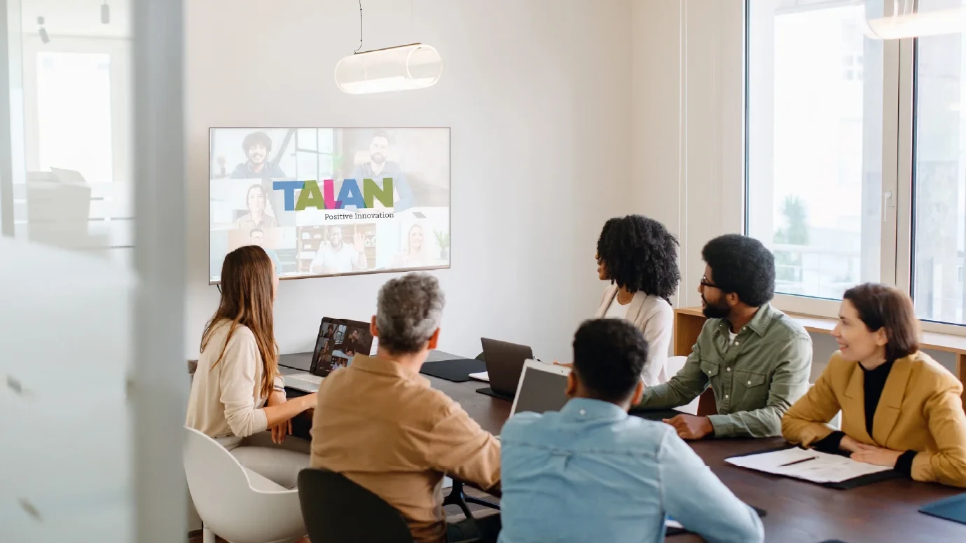 A team actively engages with remote colleagues via a large screen