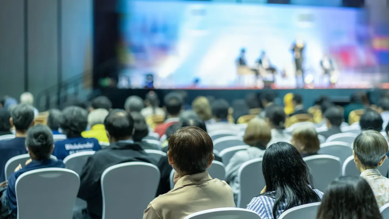 A rearview of a tech conference, where a panel of experts are talking to an audience