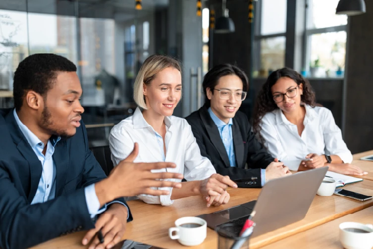 Une équipe de collègues au bureau regarde l'écran de l'ordinateur et apprend du webinaire et collabore ensemble sur les avantages et les limites de SharePoint.