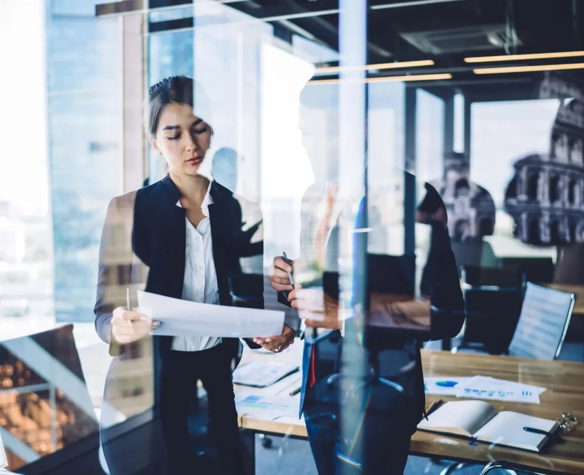 A man and a woman at an office look at some data and inforgraphs on a paper