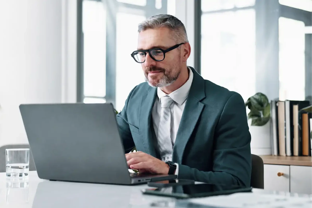 Homme responsable des opérations, des achats et des finances travaillant sur son ordinateur et prenant des notes lors du webinaire.
