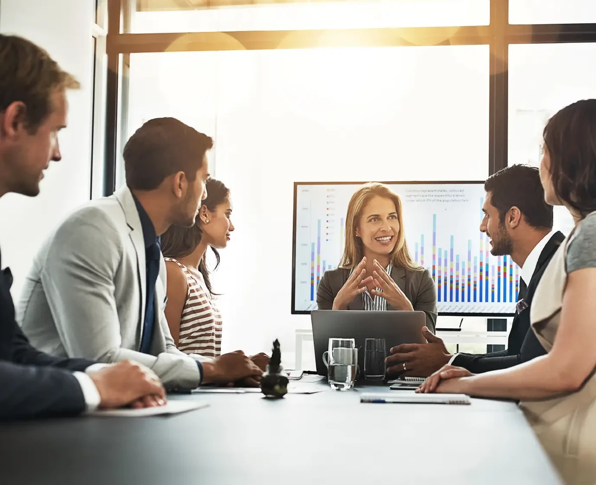 Woman at the center of a meeting analyzing data and evolving in the world of SAP Business Intelligence with people from different cultures and potential customers.