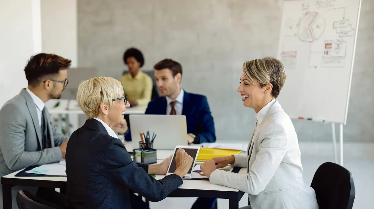 To women and two men in an office are having a friendly discussion about some work-related data