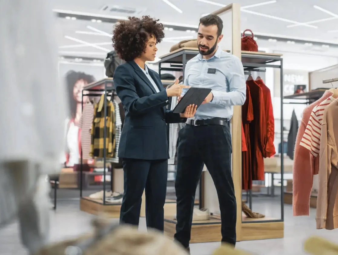 Two colleagues working together in clothing store with their modern software