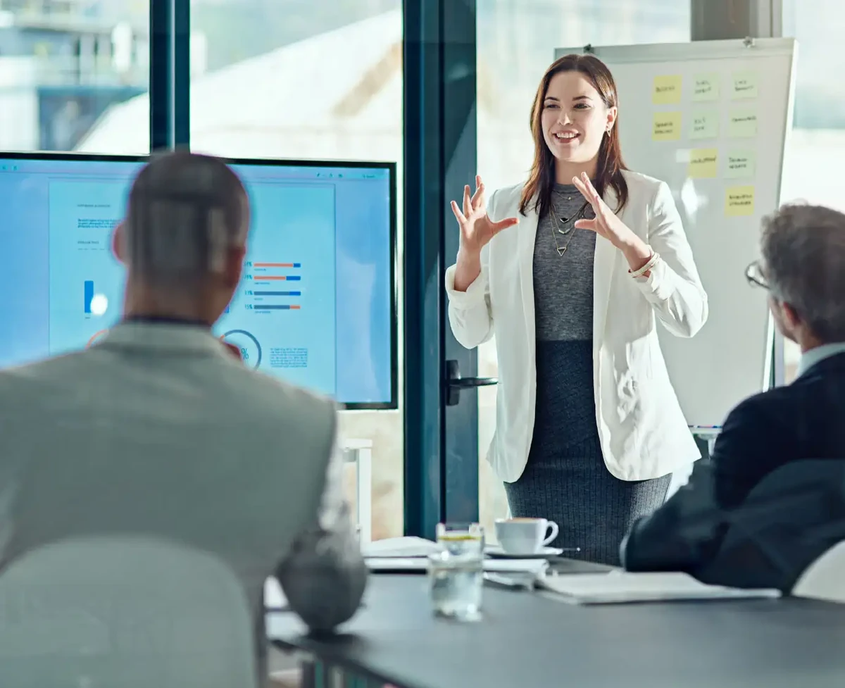 Female executive presenting on digital dashboard in front of team