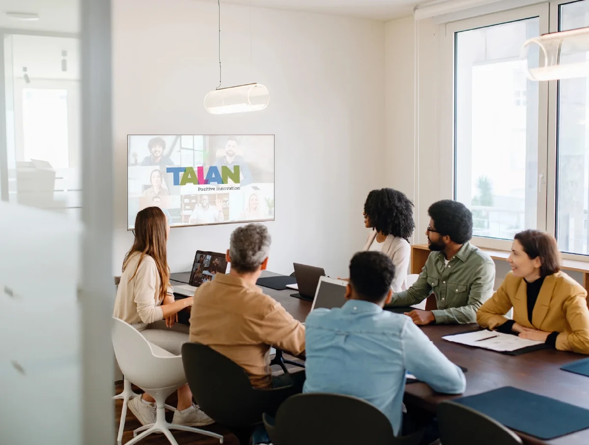 A team actively engages with remote colleagues via a large screen