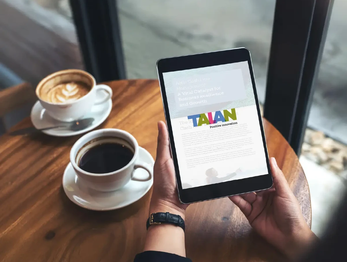 Mockup image of hands holding black tablet pc with white blank screen and coffee cups on table