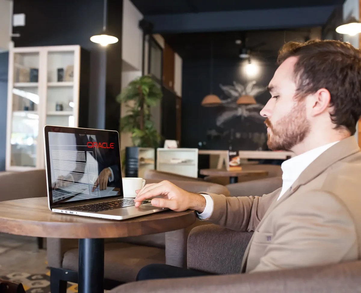 A man in a professional setting is working on the Oracle Apex form modernization on his laptop