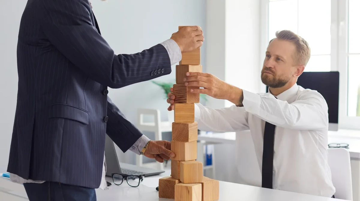 Two business leader at an office are putting the building block f a project in place and watching the project progress