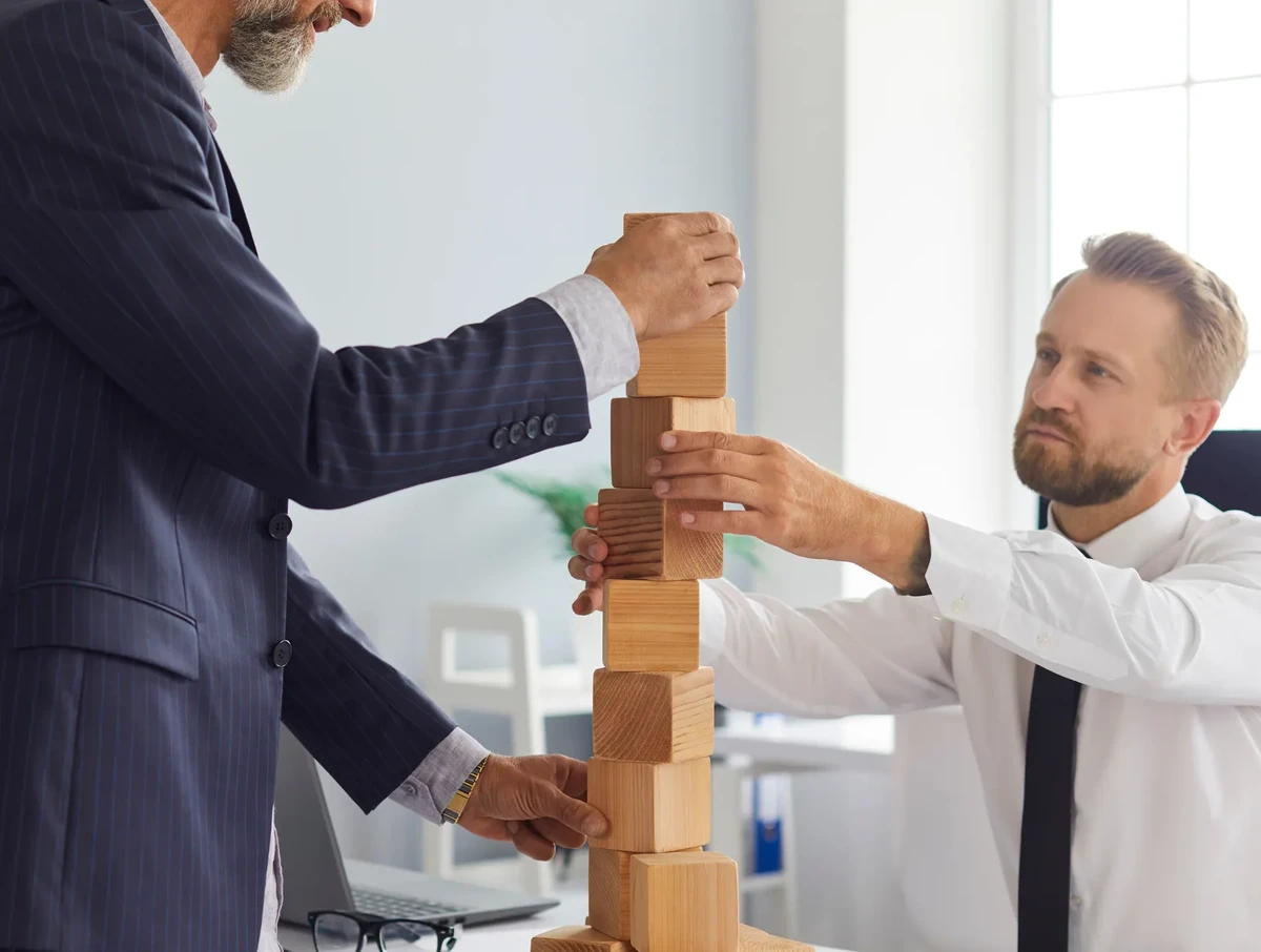 Two business leader at an office are putting the building block f a project in place and watching the project progress