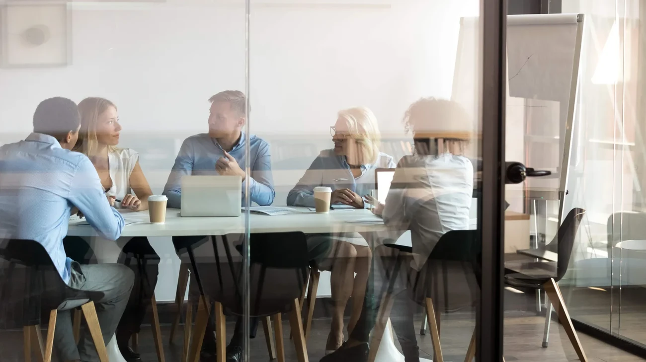 A dynamic team gathered around a desk at work and discuss some relevant data