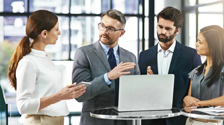 A team of professional consultants reviewing their operational performance and technology effectiveness. There are offices in the background.