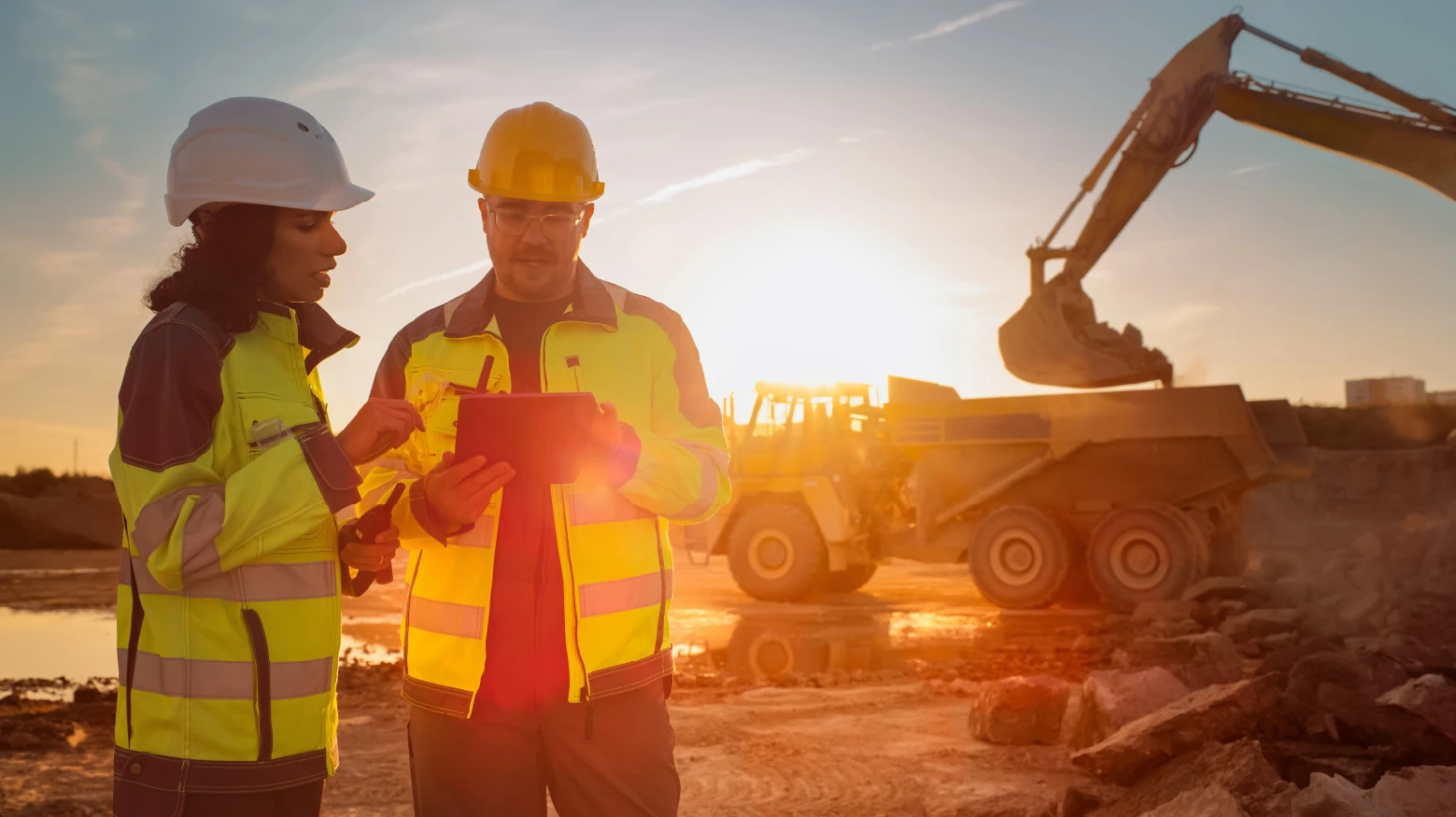 Two Talan experts guiding in a mine. Sand and mining excavation machines are seen.