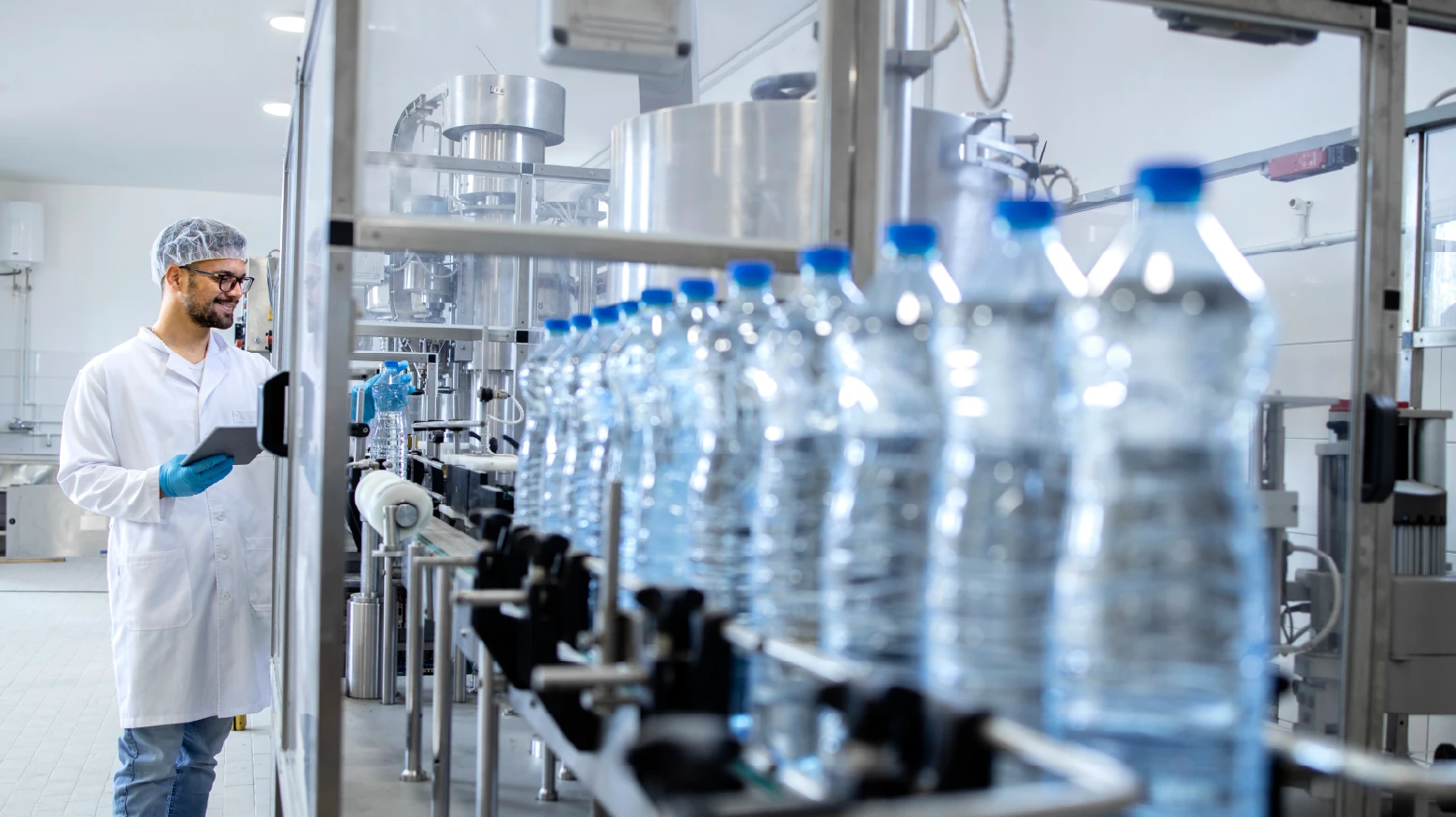 A male worker optimizing the process of his beverage bottle production line.