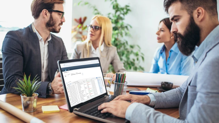 a team meeting where people are looking at the data on a computer.