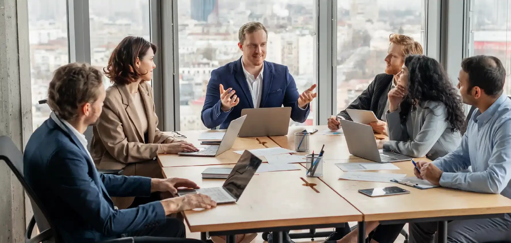 Team of people in a large office room collaborating with a partner.