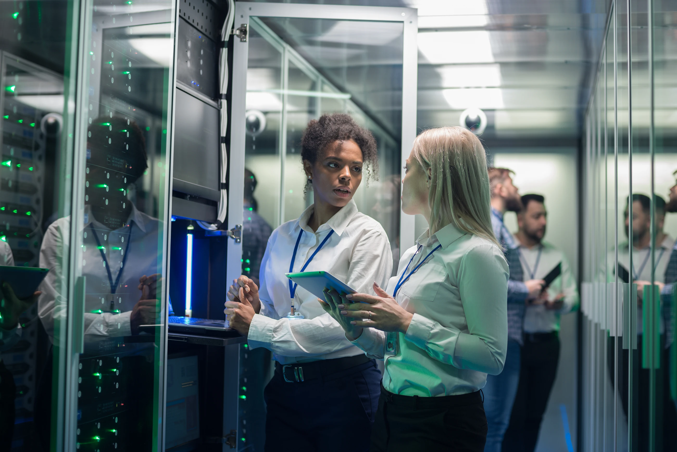 Female colleagues working in a data centre with rows of server racks 