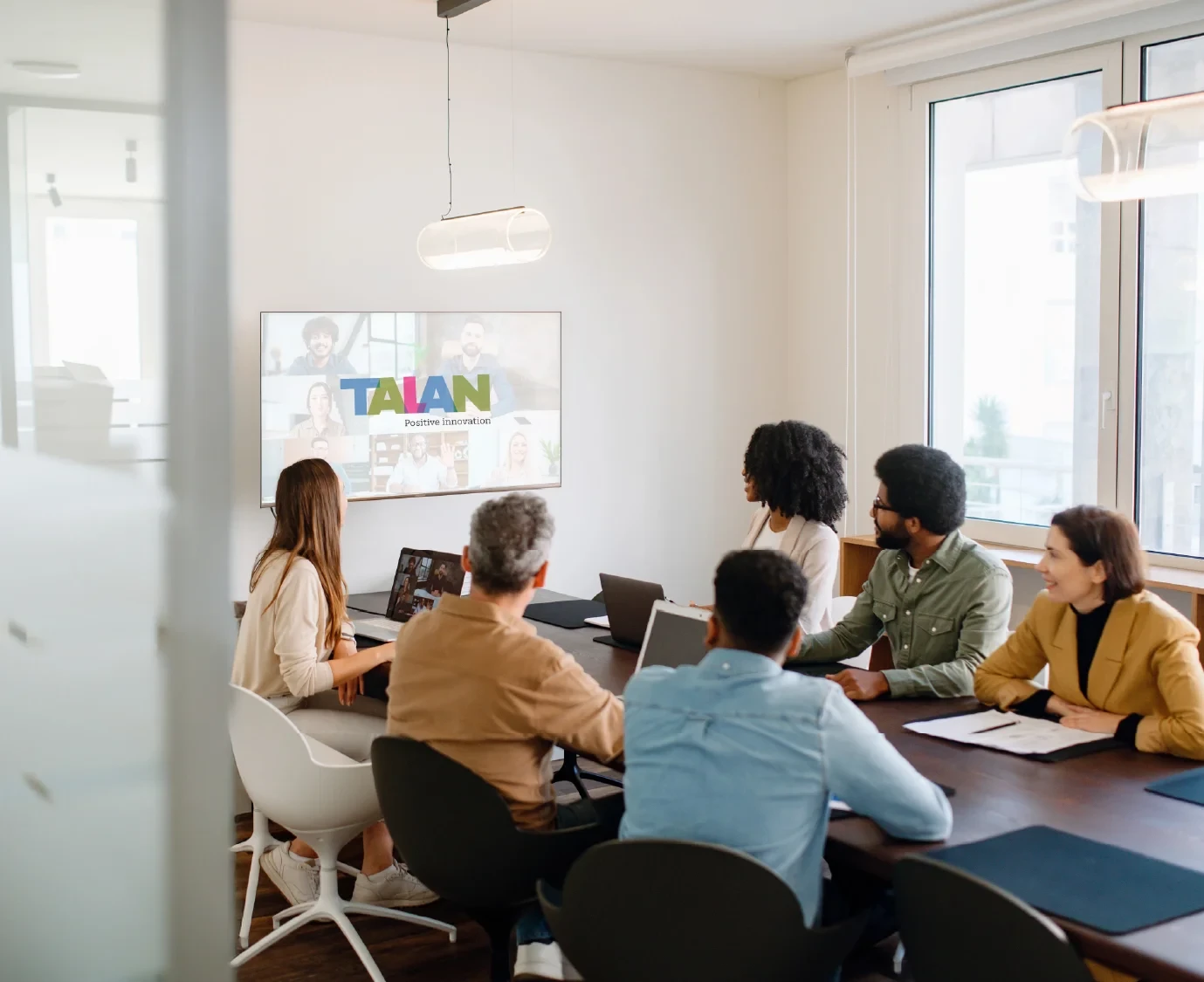 A team actively engages with remote colleagues via a large screen