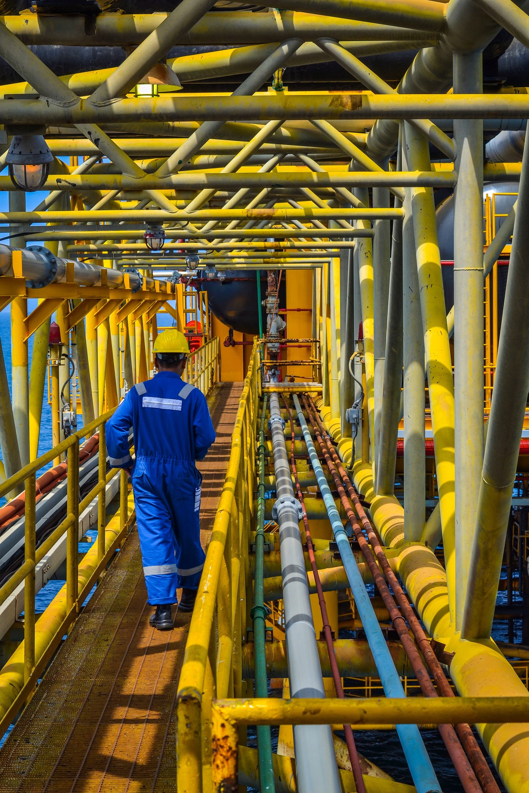 A construction worker walking along pipelines.