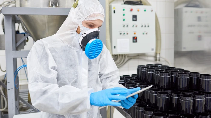 Professional chemist on production line with software that improves efficiency and safety for chemical manufacturers.