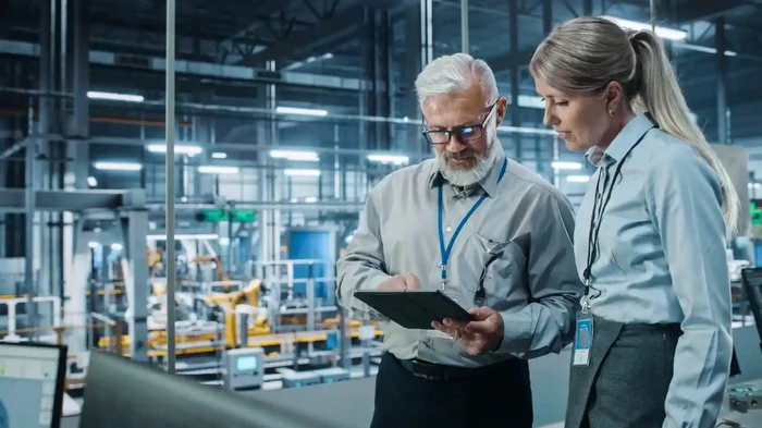 Two professionals working in a manufacturing plant with a tablet using SAP BTP