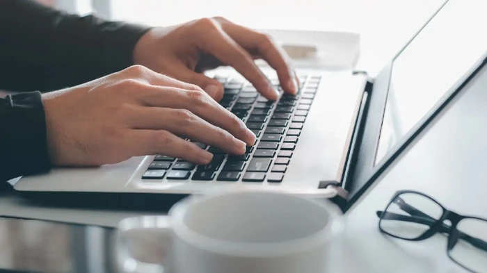Computer with a person filling out a form.