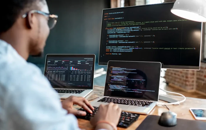 An engineer is working with an Oracle system with three monitors opened in front of him