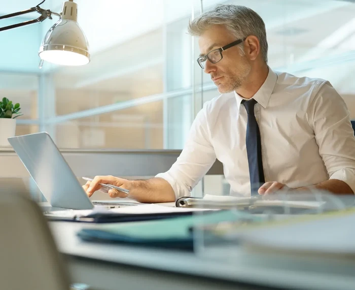 Businessman in office working at desk on laptop computer