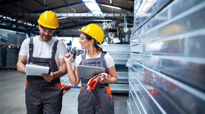Two workers in a manufactoring company looking at some data on a tablet